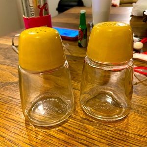 Vintage salt and pepper shaker. Yellow tops plastic with glass bottoms.